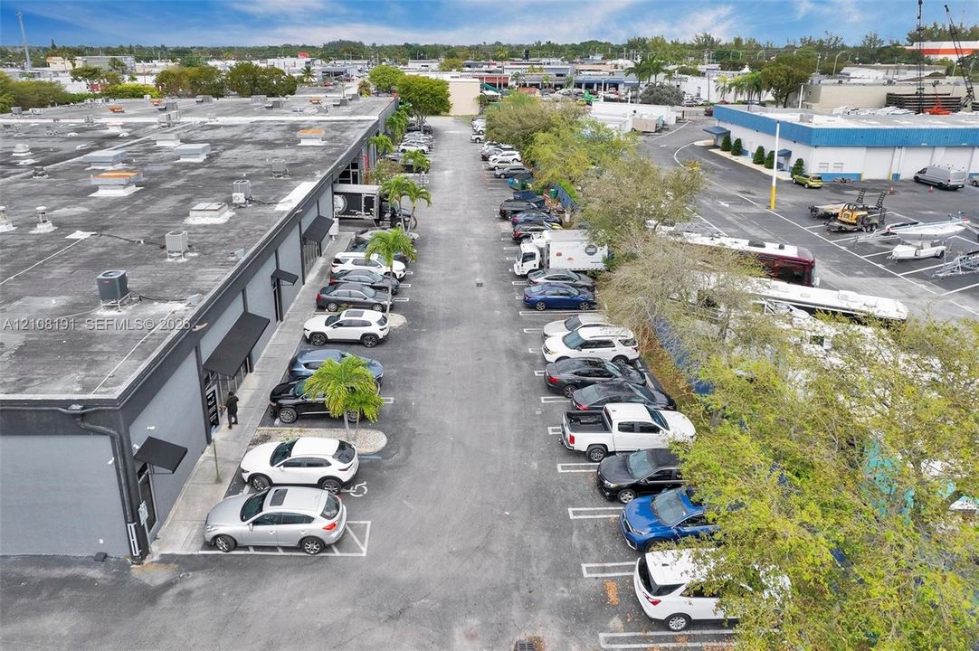 Commercial property featuring gray industrial exterior siding, designated paved surface parking, metal awnings over entryway points, and established perimeter landscaping