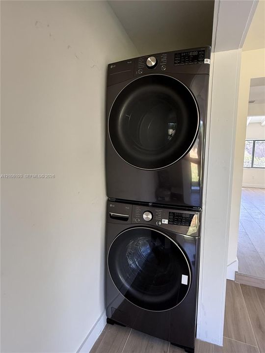 Stacked metallic-finish front-load laundry unit featuring integrated digital control panels