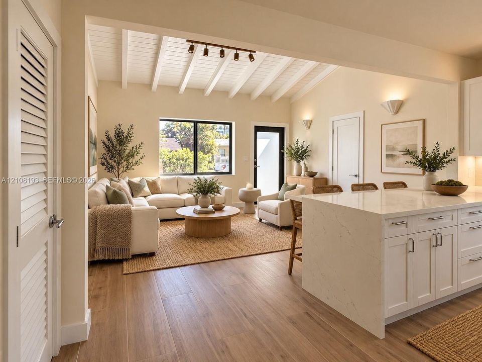 Vaulted ceiling with exposed white beams, wood-finish flooring, island with stone-surface countertop, white shaker-style cabinetry, and track lighting