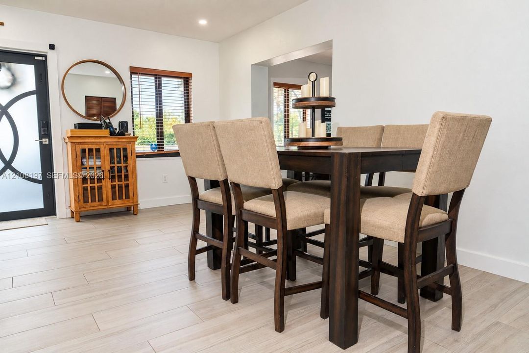 Ceramic tile flooring, recessed ceiling lighting, and a modern entry door featuring geometric glass paneling