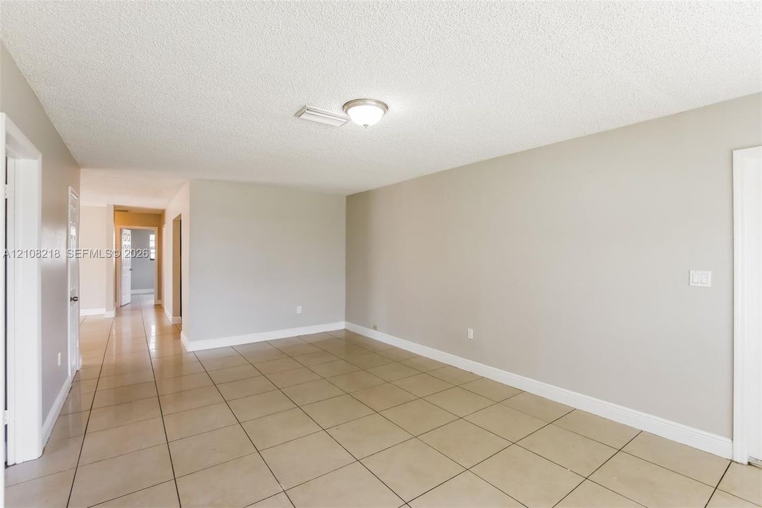 Neutral-toned interior space featuring light-colored square floor tiling, crisp white door frames, and a flush-mount ceiling light fixture
