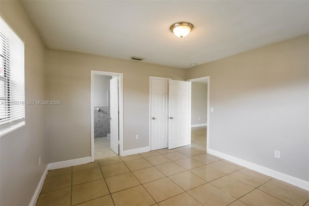 Interior room featuring neutral-toned walls, tile flooring, a flush-mount ceiling light fixture, and two sets of white six-panel interior doors