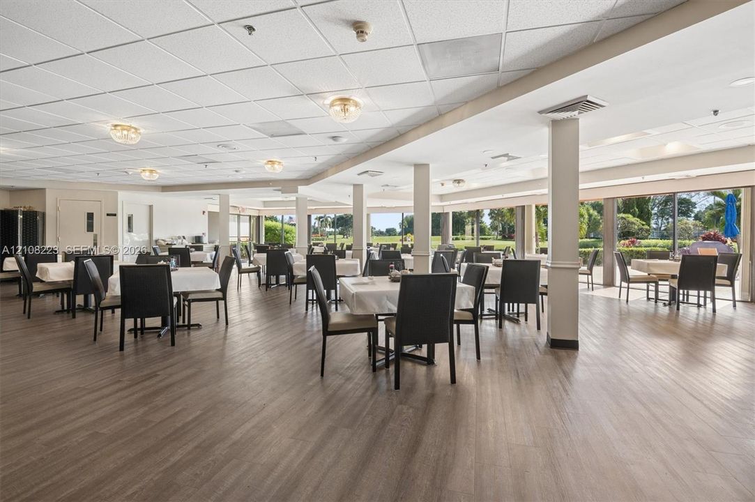 Open-concept interior featuring wood-finish flooring, drop ceiling panels, structural support columns, and large-format glass sliding doors