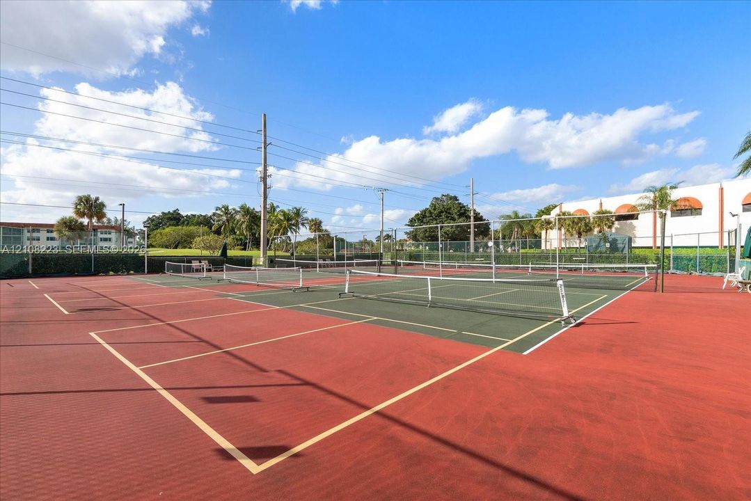 Multi-court tennis facility featuring surfaced playing areas, perimeter fencing, and net systems
