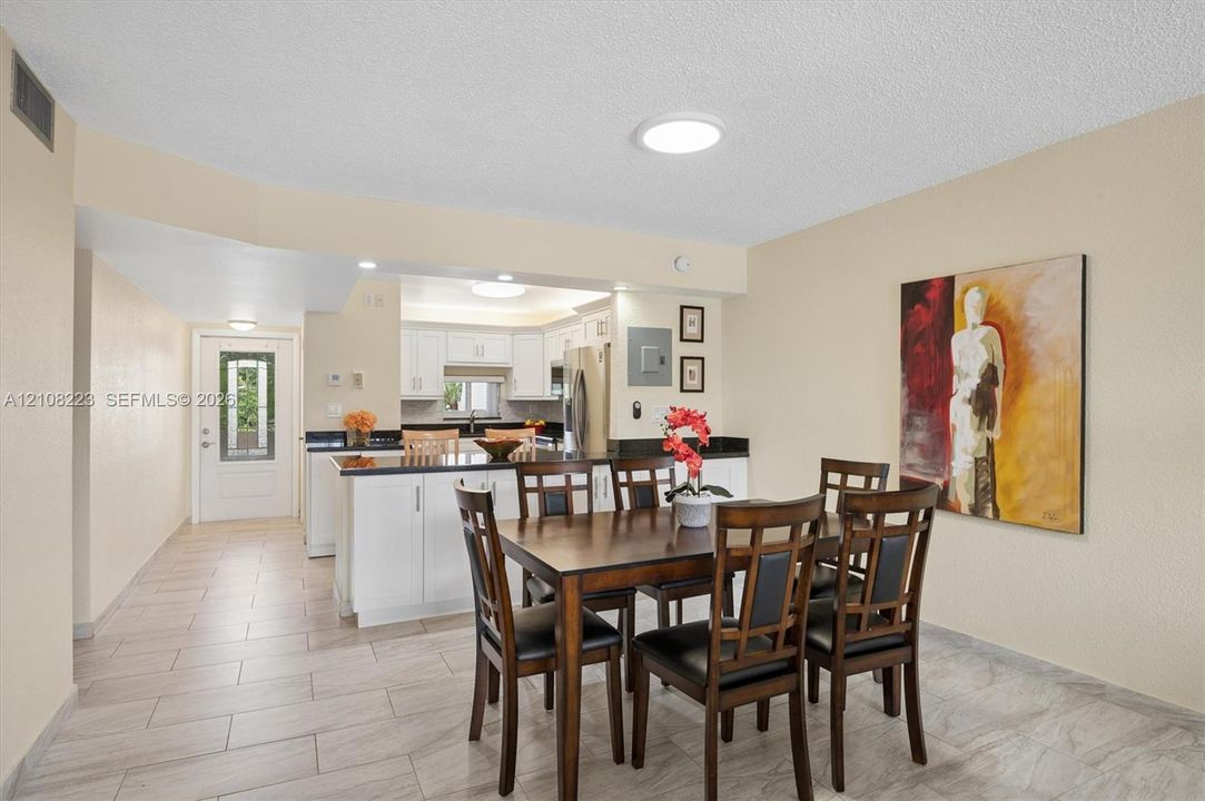 Kitchen featuring white cabinetry, dark countertops, tile flooring, and a glass-paneled exterior entry door