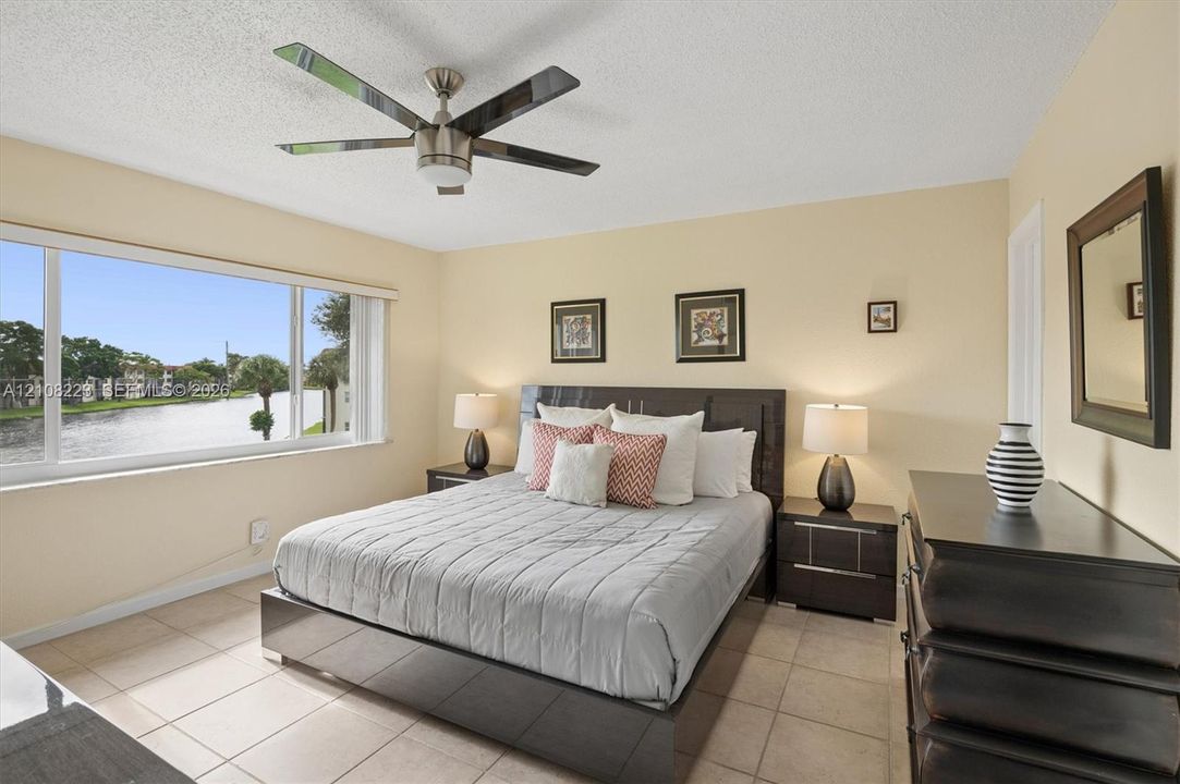 Large window with water scenery, tile flooring, and a ceiling fan with integrated lighting