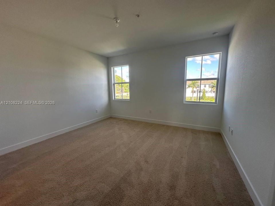 Neutral interior room featuring plush carpeting and two multi-pane windows