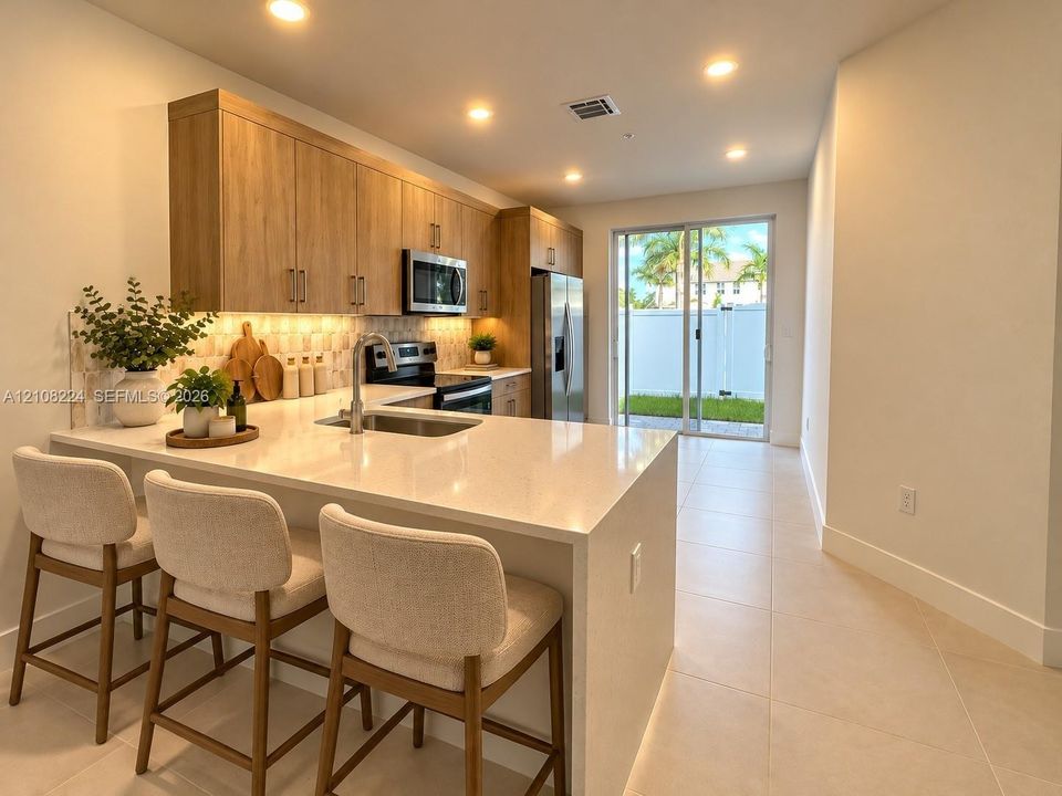 Kitchen featuring light wood-finish cabinetry, quartz countertops, an undermount sink, stainless steel appliances, and recessed lighting