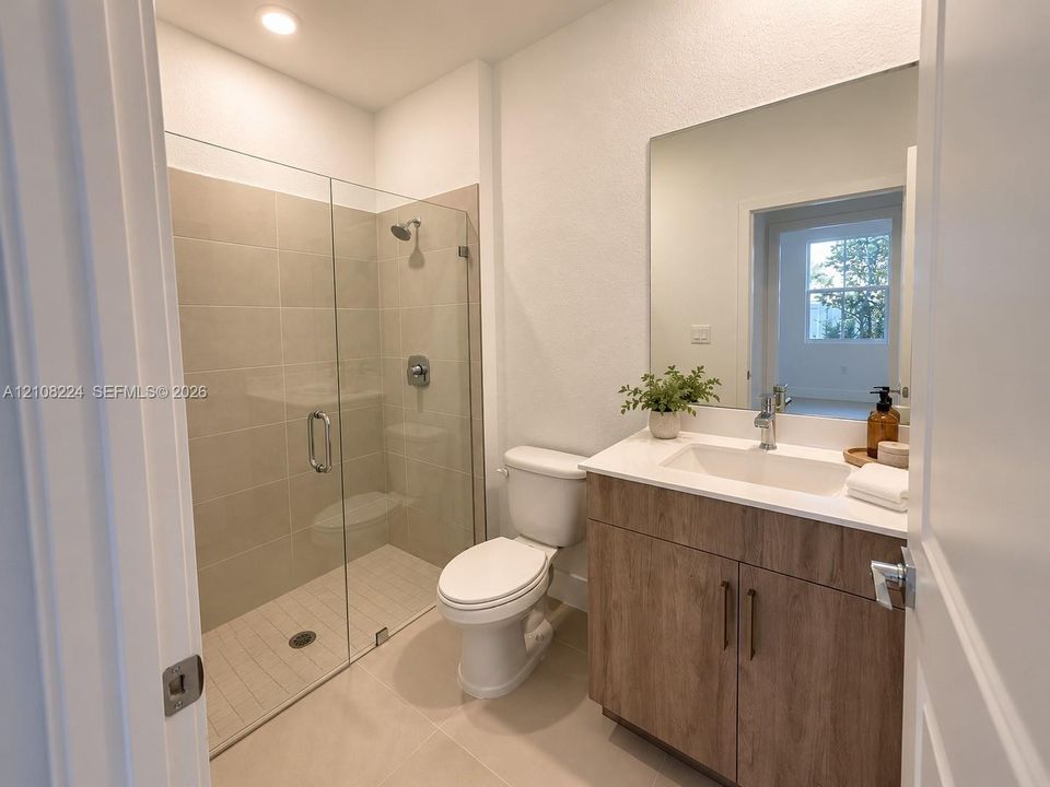 Bathroom featuring a glass-enclosed shower with tiled surround, wood-finish vanity cabinetry, a rectangular undermount sink, a stone-surface countertop, and a wall-mounted mirror