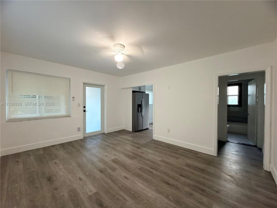 Interior space featuring wood-finish flooring, a neutral color palette, a ceiling-mounted light fixture, and an exterior door with glass paneling