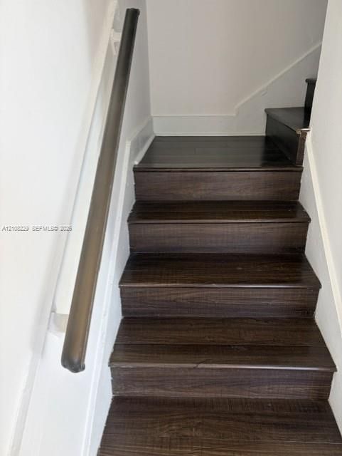 Staircase featuring dark-toned wood-finish treads and a coordinating round handrail