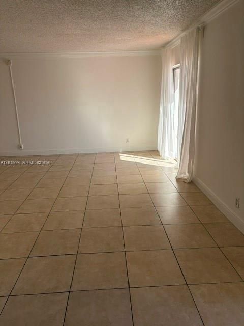 Room featuring neutral-toned tile flooring, textured ceiling finish, and a sliding glass door