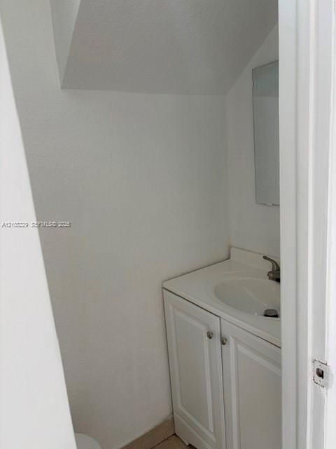 Vanity cabinet with white raised-panel doors, integrated sink countertop, single-handle faucet, and wall-mounted mirror