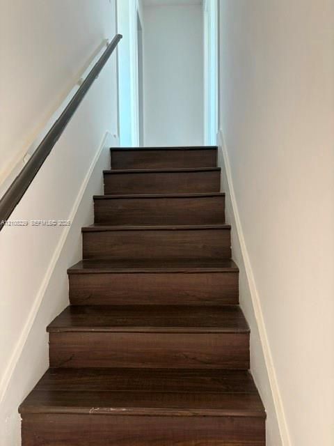 Staircase featuring wood-finish treads and a dark-toned handrail