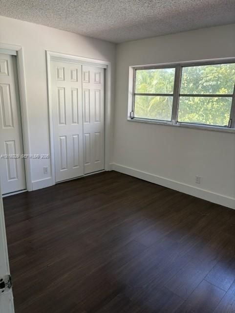 Room featuring wood-finish flooring, dual panel closet doors, and a single-pane horizontal window