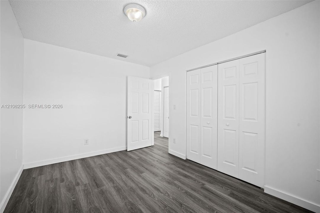 Neutral room featuring wood-finish flooring, double-panel closet doors, and a ceiling-mounted light fixture