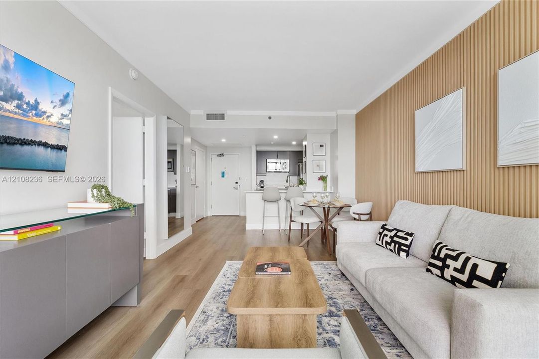 Living area featuring wood-finish flooring, vertical slat wood wall paneling, and an open-concept layout with kitchen breakfast bar