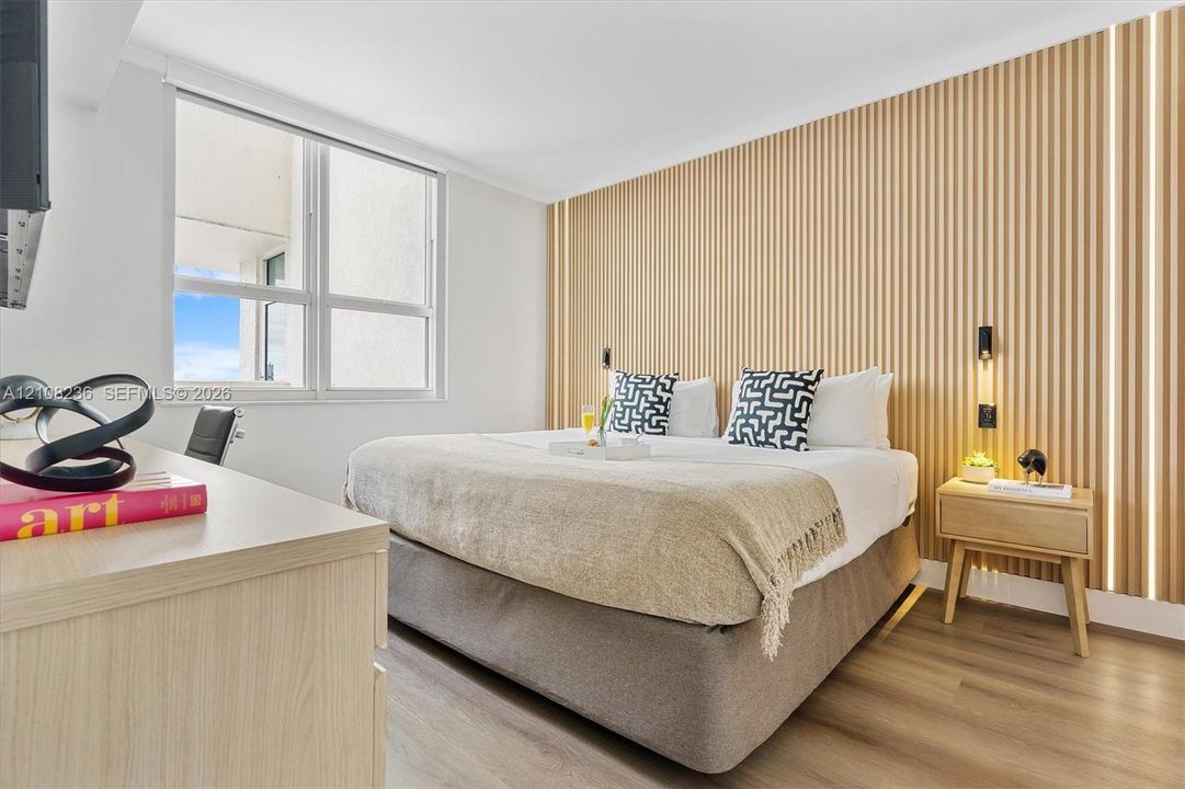 Bedroom featuring wood-slat accent wall paneling, integrated linear lighting, and wood-finish flooring
