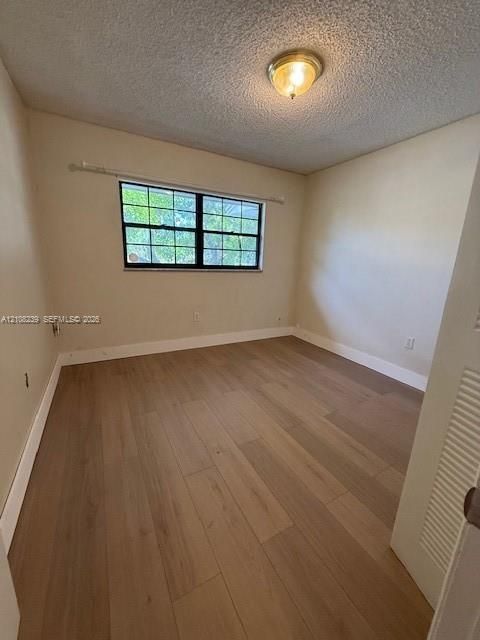 Wood-finish flooring, multi-pane window with black frame, and flush-mount ceiling lighting
