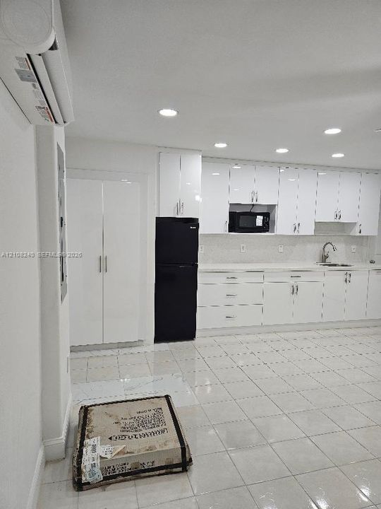 Kitchen featuring high-gloss white cabinetry, recessed lighting, tile flooring, and a wall-mounted ductless climate control unit