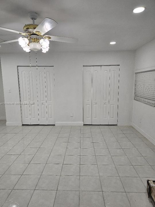 Neutral-toned tile flooring, recessed ceiling lighting, multi-light ceiling fan, and two sets of interior bi-fold closet doors