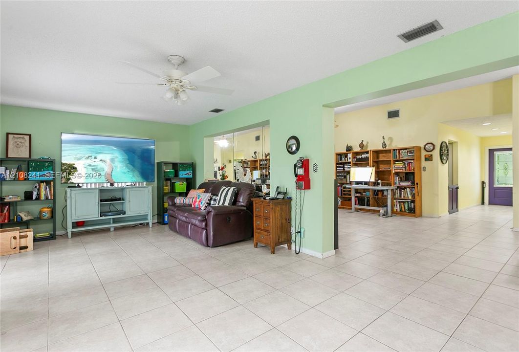 Spacious interior featuring ceramic tile flooring, built-in wooden shelving, and a ceiling fan with integrated lighting