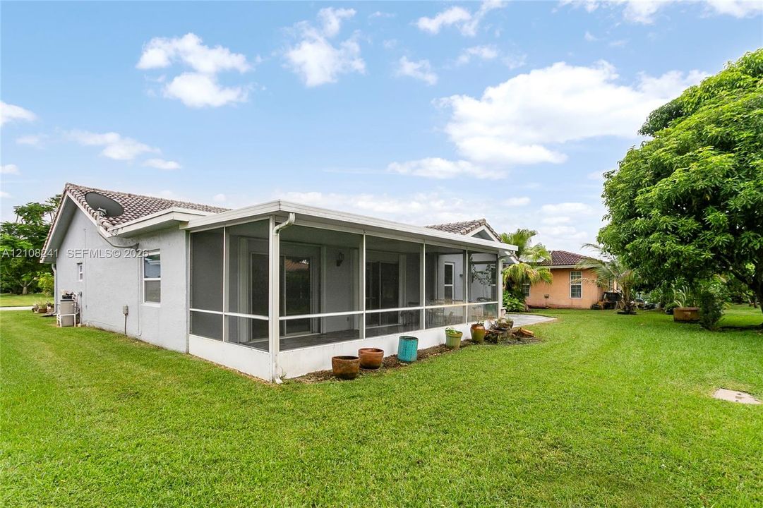 Screened-in rear porch featuring a concrete foundation, stucco exterior walls, and a tiled roof