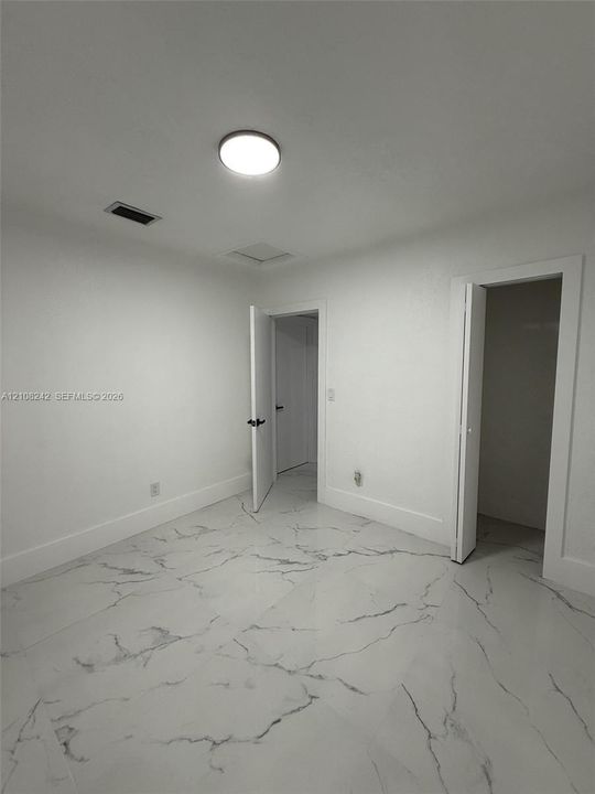 Interior space featuring polished stone-finish flooring with marbled veining and a flush-mount ceiling light fixture