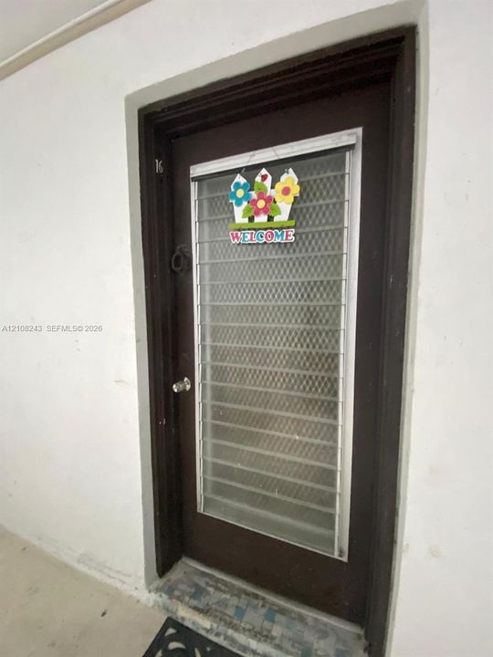 Dark-toned solid core entry door featuring a full-length metal security screen insert and integrated round-knob hardware