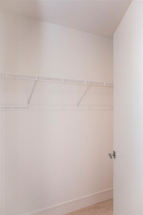 Storage space featuring a white wire shelving system, a mounted garment rod, and neutral flooring