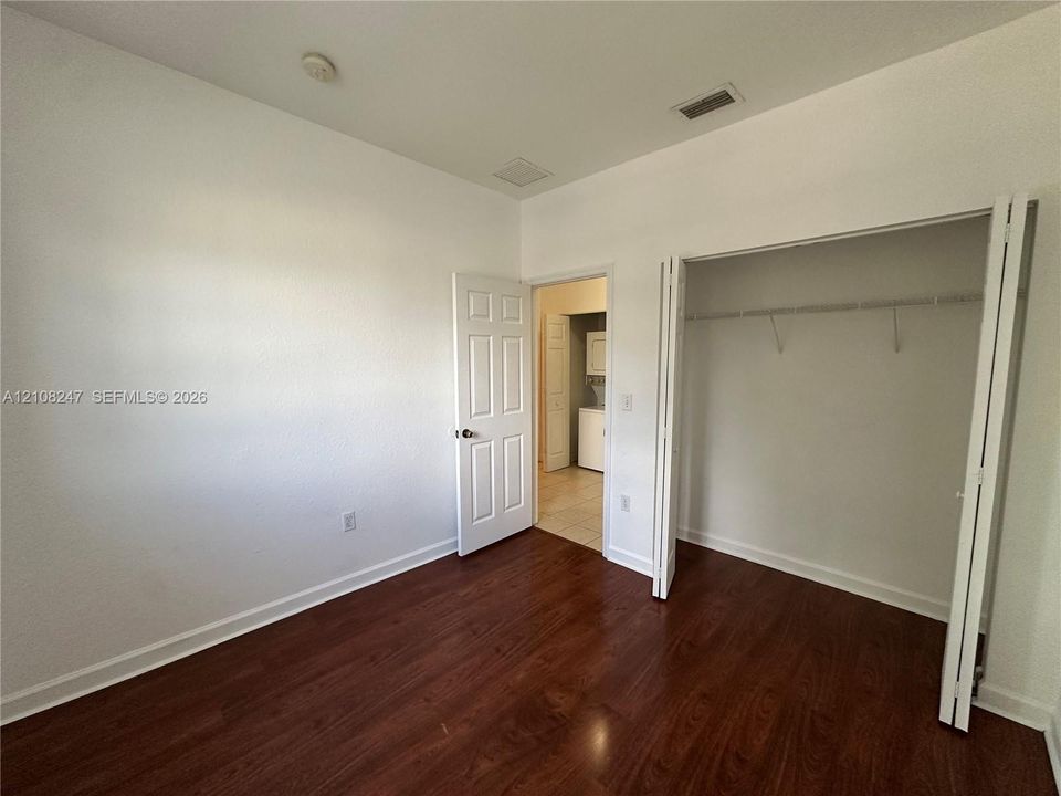 Interior space featuring wood-finish flooring, a bi-fold door closet with built-in shelving, and a six-panel interior door