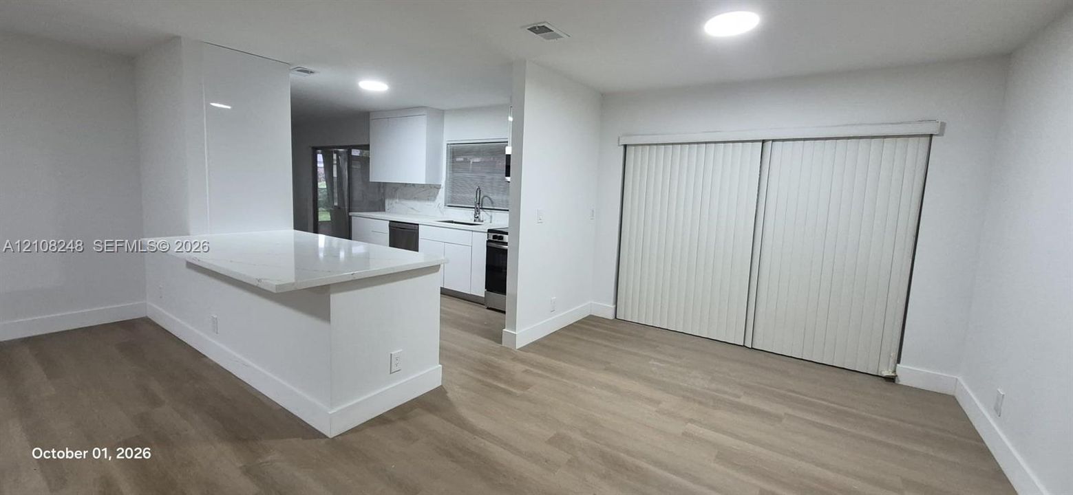 Kitchen featuring white cabinetry, stone-finish countertops, stainless steel appliances, wood-finish flooring, and sliding glass doors