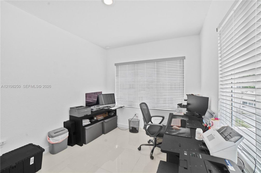 Neutral-toned ceramic flooring, recessed ceiling lighting, and large windows featuring horizontal blinds