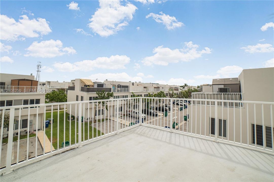 Elevated balcony featuring a smooth concrete surface and white metal railing