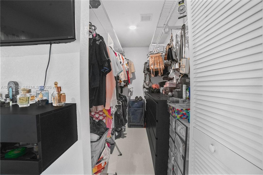 Walk-in storage space featuring white louvered doors and wire shelving