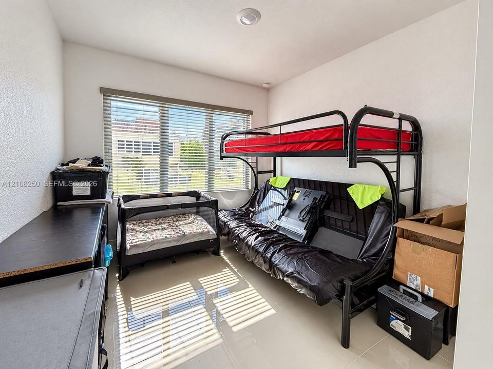 Interior space featuring large-format tile flooring, neutral wall paint, and a wide window with horizontal blinds