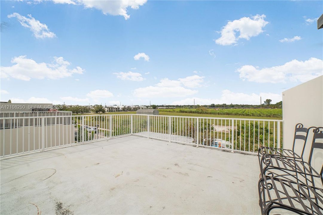 Expansive balcony featuring concrete flooring and a white vertical-slat metal railing