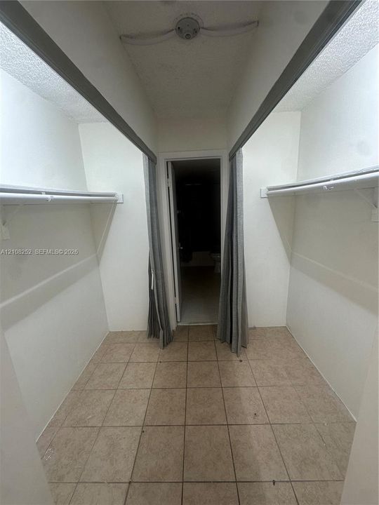 Walk-in storage space featuring tile flooring and dual wall-mounted shelving units