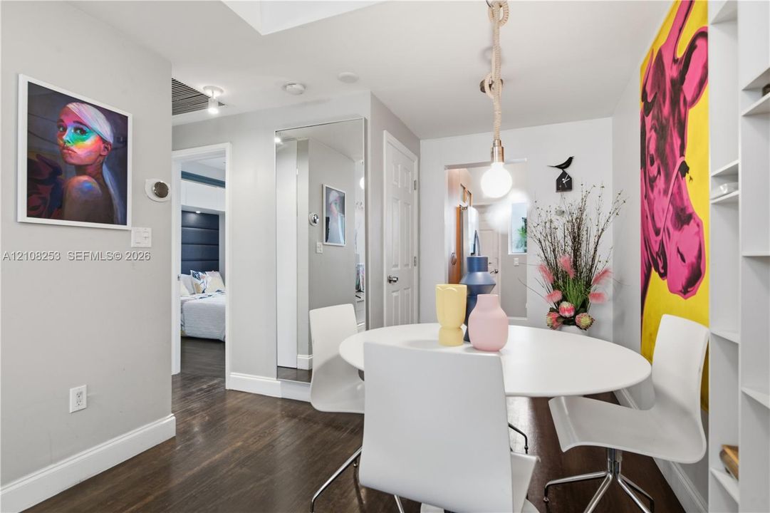 Dark-stained wood-finish flooring, floor-to-ceiling wall mirror, recessed ceiling lighting, rope-suspended pendant light, and built-in shelving unit