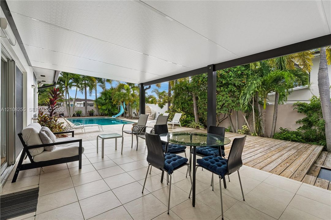 Covered patio with neutral tile flooring, wood decking, and a swimming pool