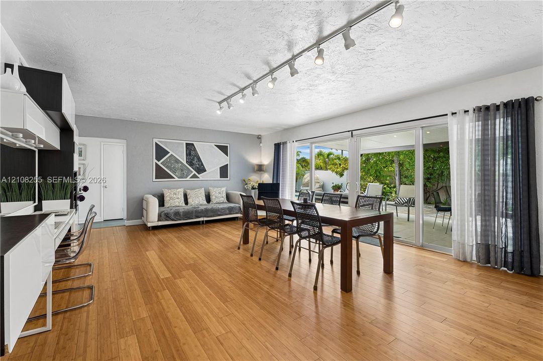 Living space featuring wood-finish flooring, ceiling-mounted track lighting, and expansive sliding glass doors