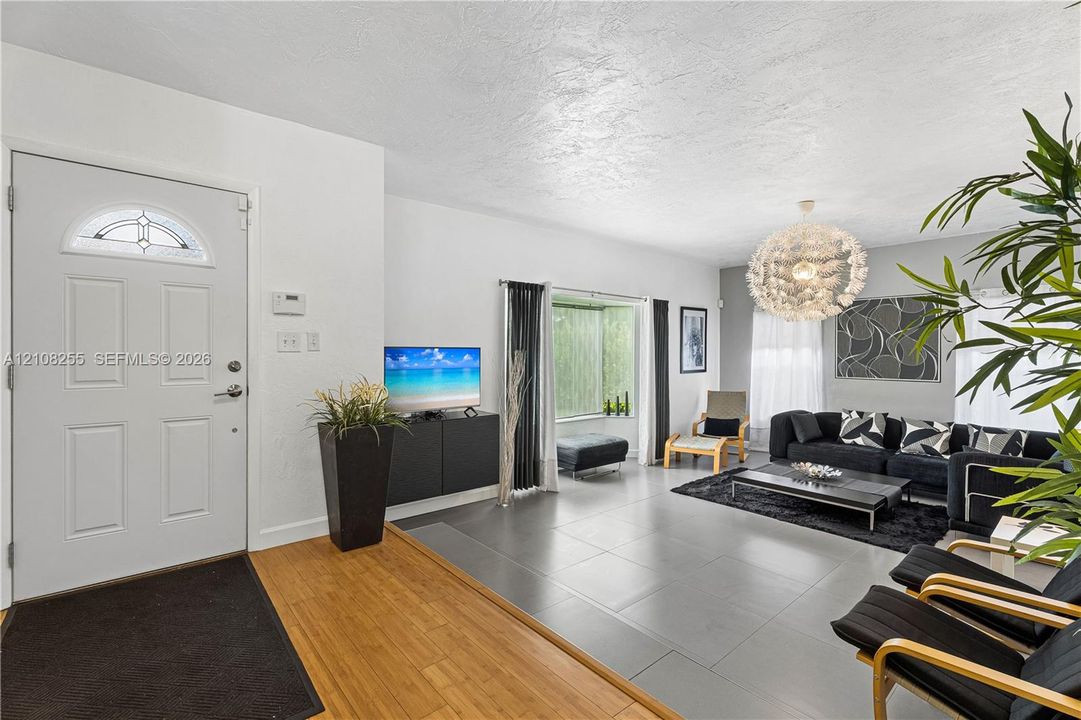 Entrance featuring a semi-circular transom window, large-format tile flooring, wood-finish entryway flooring, and a spherical tiered chandelier