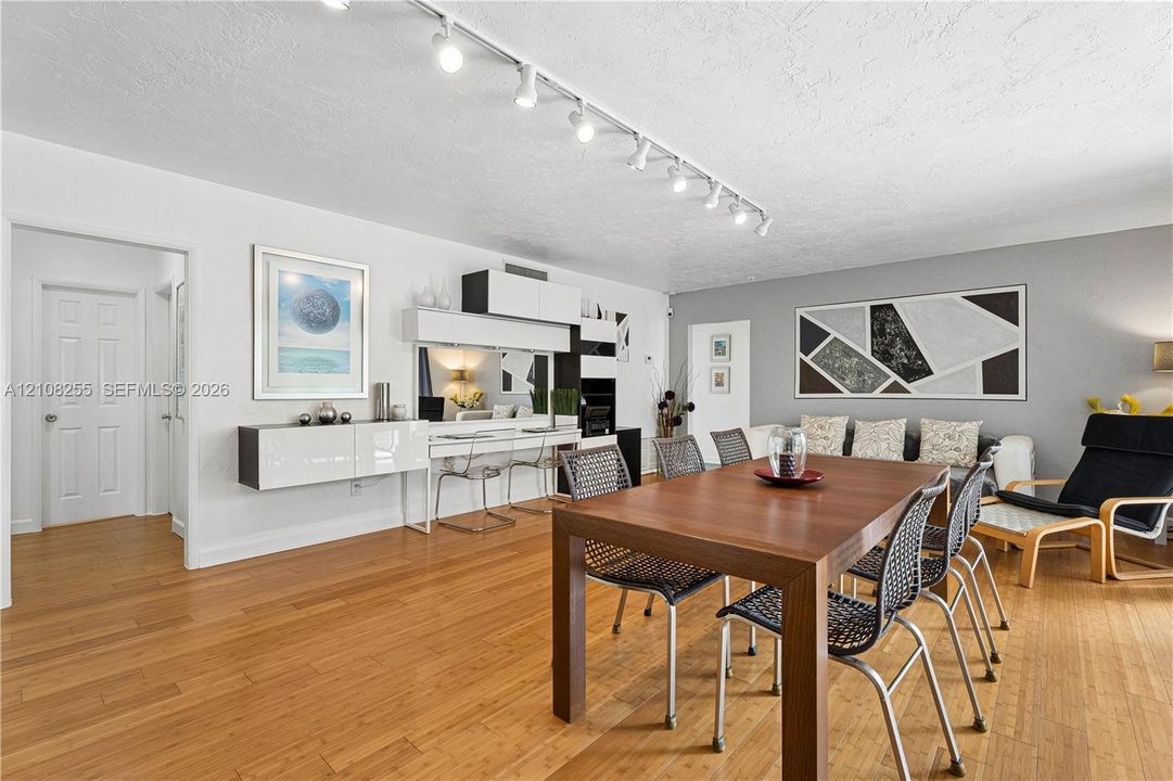 Living area featuring wood-finish flooring, ceiling-mounted track lighting, and built-in wall cabinetry with integrated desk surface