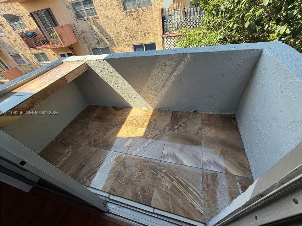 Private balcony featuring tile flooring and a built-in stone-finish ledge
