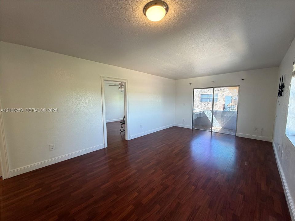Interior space featuring wood-finish flooring, sliding glass patio doors, and a flush-mount ceiling light fixture