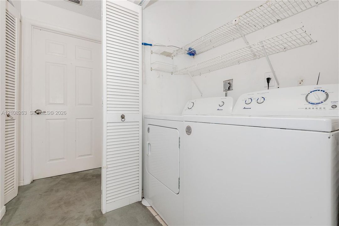 Laundry area featuring louvered bi-fold closet doors, wall-mounted wire shelving, and a paneled interior door