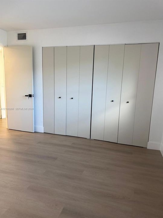 Wood-finish flooring, full-wall built-in cabinetry with neutral panel doors, matte black hardware, and crisp white wall finishes