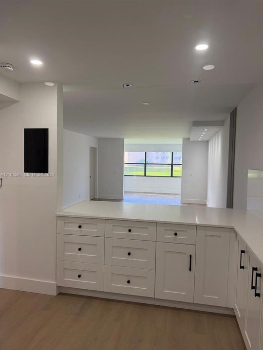Kitchen featuring white cabinetry with matte black hardware, stone-finish countertops, recessed lighting, and wood-finish flooring