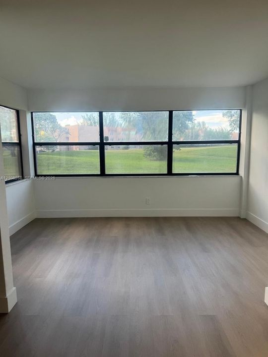 Interior space featuring wood-finish flooring, neutral walls, and floor-to-ceiling windows with dark framing