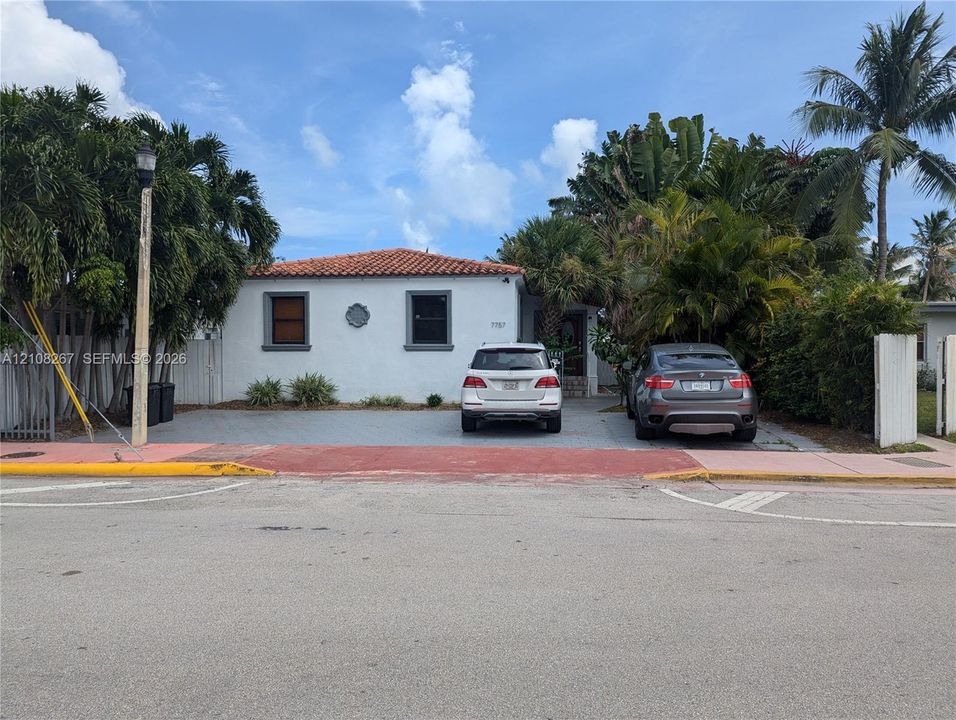 Stucco exterior featuring a terracotta tile roof, paved driveway, and mature landscaping